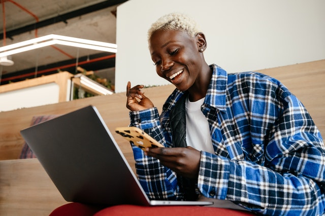 woman happy looking at phone and laptop